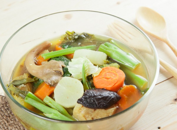 Fresh hot vegetable soup and spoon on wood